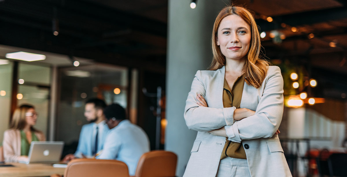 1. A woman in a suit stands confidently before a group of people, engaging them with her presentation.