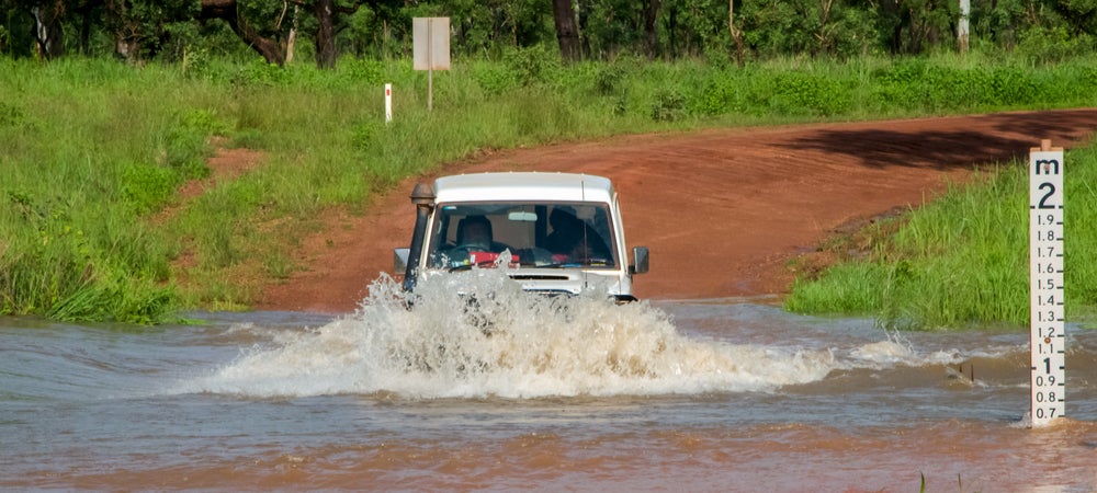 A large Four-Wheel-Drive drives through a flooded road in the Northern Territory.