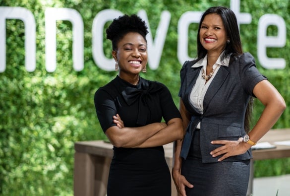 Two business leaders stand in front of a sign that says ‘innovation.’