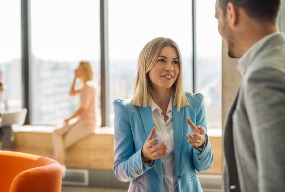 A male and a female business professional having an informal discussion about a business strategy in a bright office space.