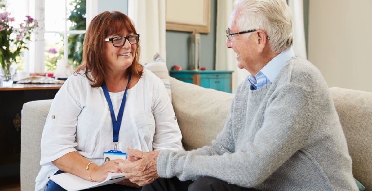 A mental health worker helping an elderly adult.