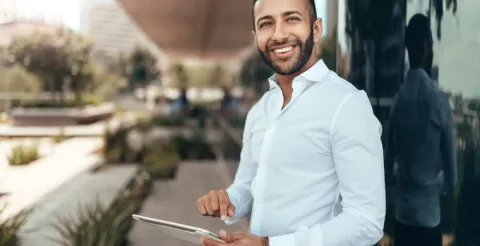 A man smiling at the sky while holding a clipboard and reviewing course data.