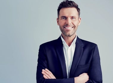 A smiling professional who has advanced their career in finance.