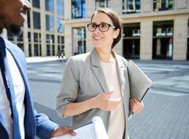 Two finance experts conversing as they walk down the street.