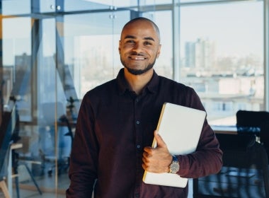 A smiling NGO worker holding a laptop.